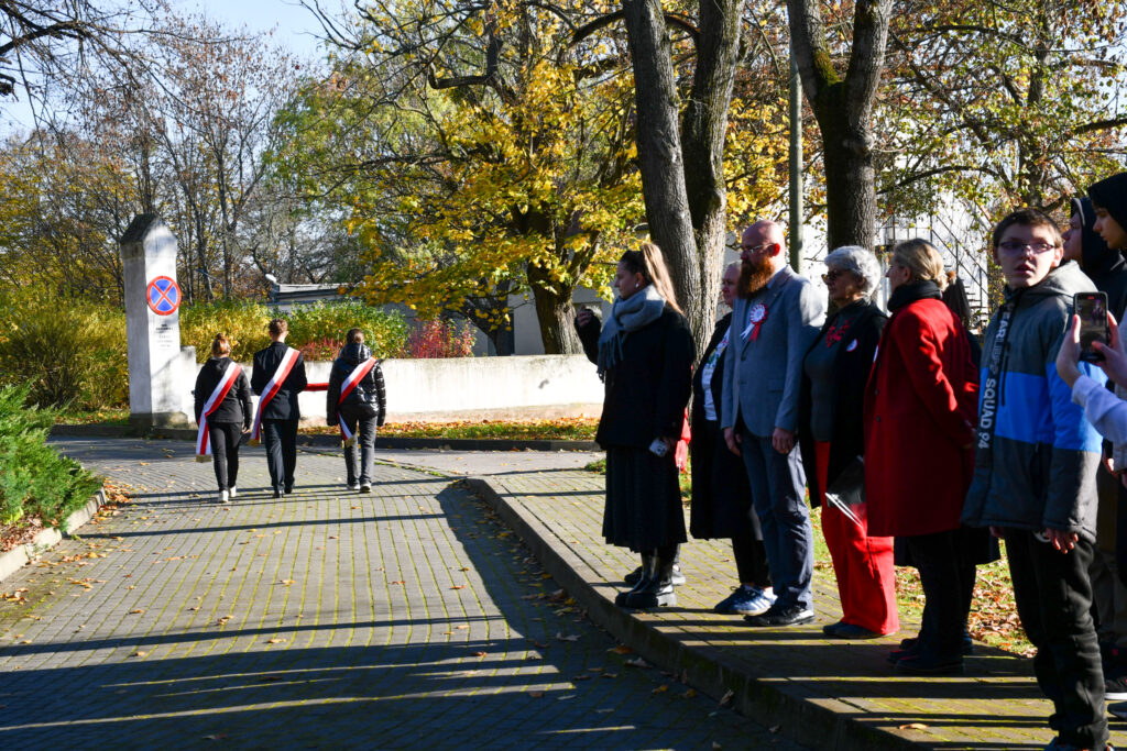 Na pierwszym planie uczestnicy uroczystości patriotycznej. W tle Poczet Sztandarowy.