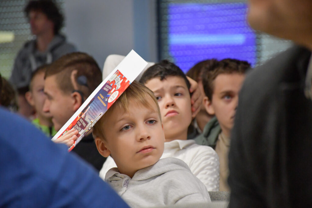 Zbliżenie na ucznia słuchającego wystąpienia podczas uroczystości.