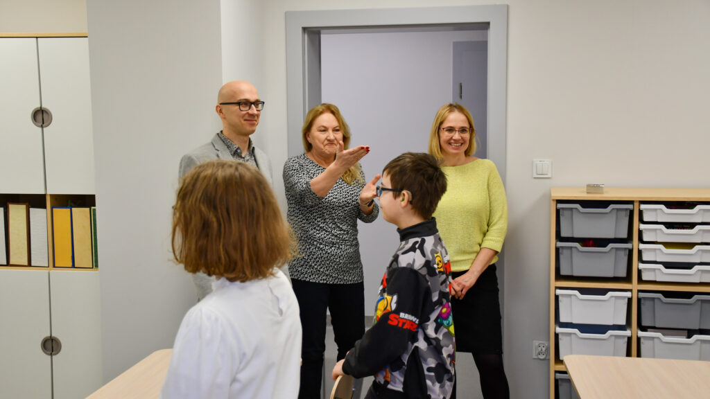 Nauczyciele i uczniowie rozmawiają w klasie podczas otwarcia nowej pracowni.