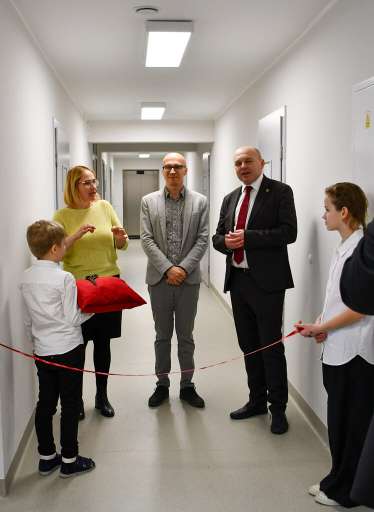 Przemówienie w korytarzu przed przecięciem wstęgi, uczniowie stoją obok nauczycieli.