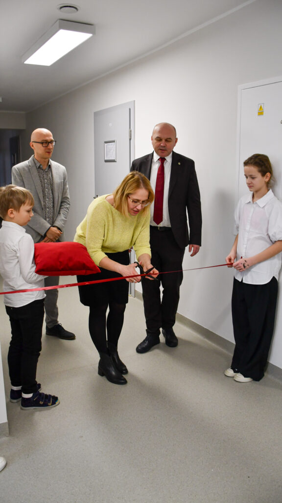 Kobieta przecina wstęgę podczas oficjalnego otwarcia w szkolnym korytarzu.