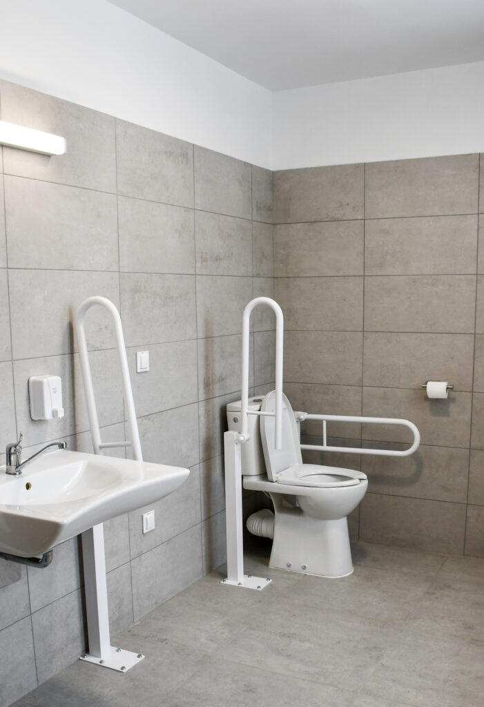 Dostosowana łazienka szkolna z uchwytami dla osób z niepełnosprawnościami.