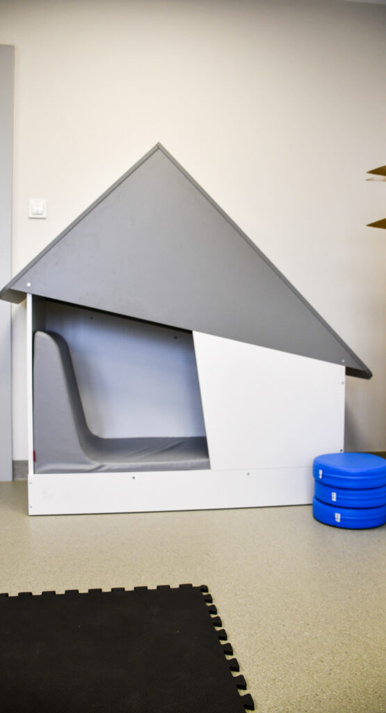 Mała strefa wyciszenia z zabudowaną budką terapeutyczną i poduszkami do siedzenia.